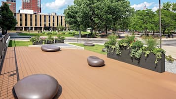 A spacious outdoor area with a wooden deck, large seating areas, and planters with greenery.