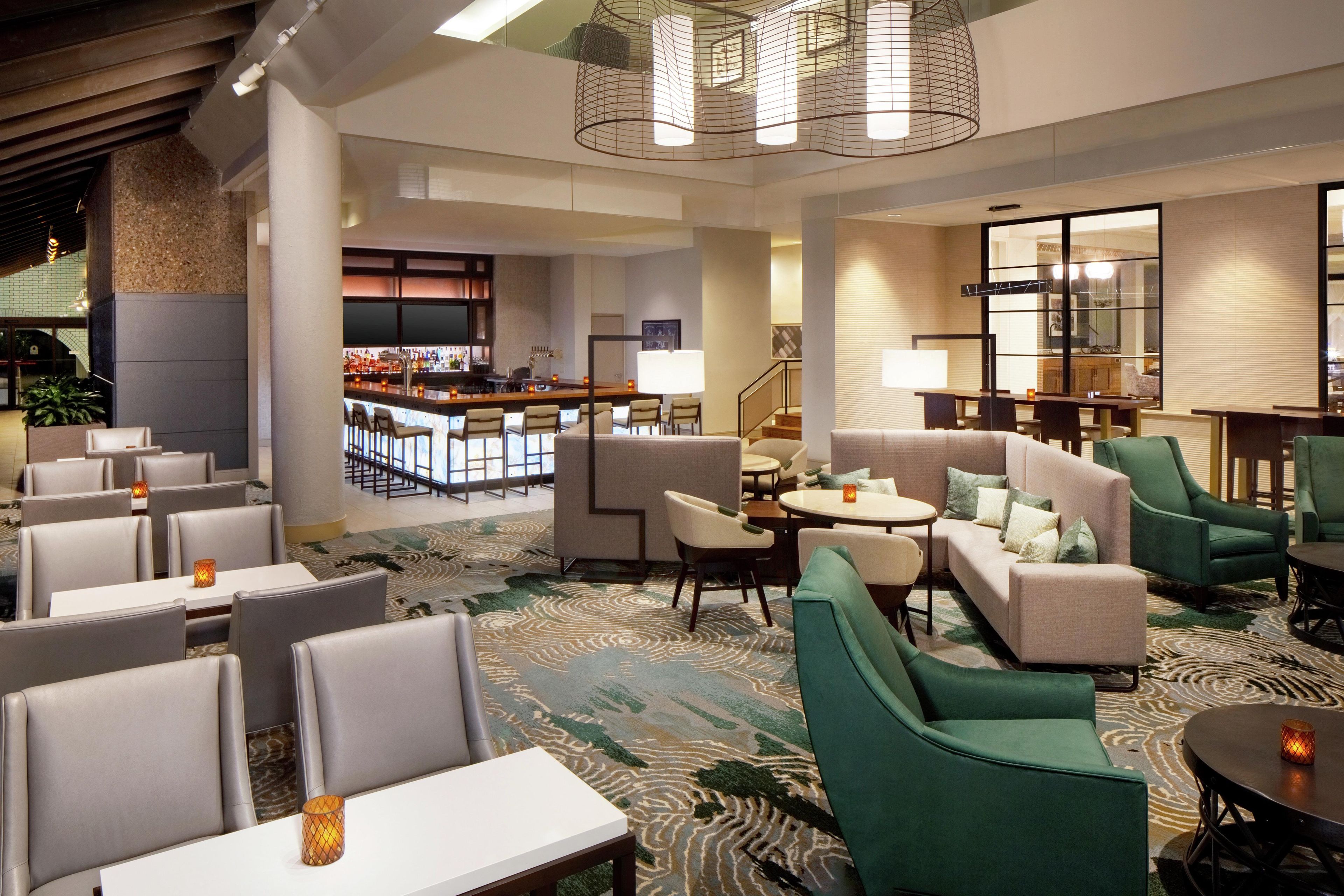 A hotel lobby with seating areas, a bar, and a staircase.