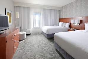 A hotel room with two beds, a TV, a desk, and a large window with curtains. - Courtyard by Marriott Dallas North (Dallas)