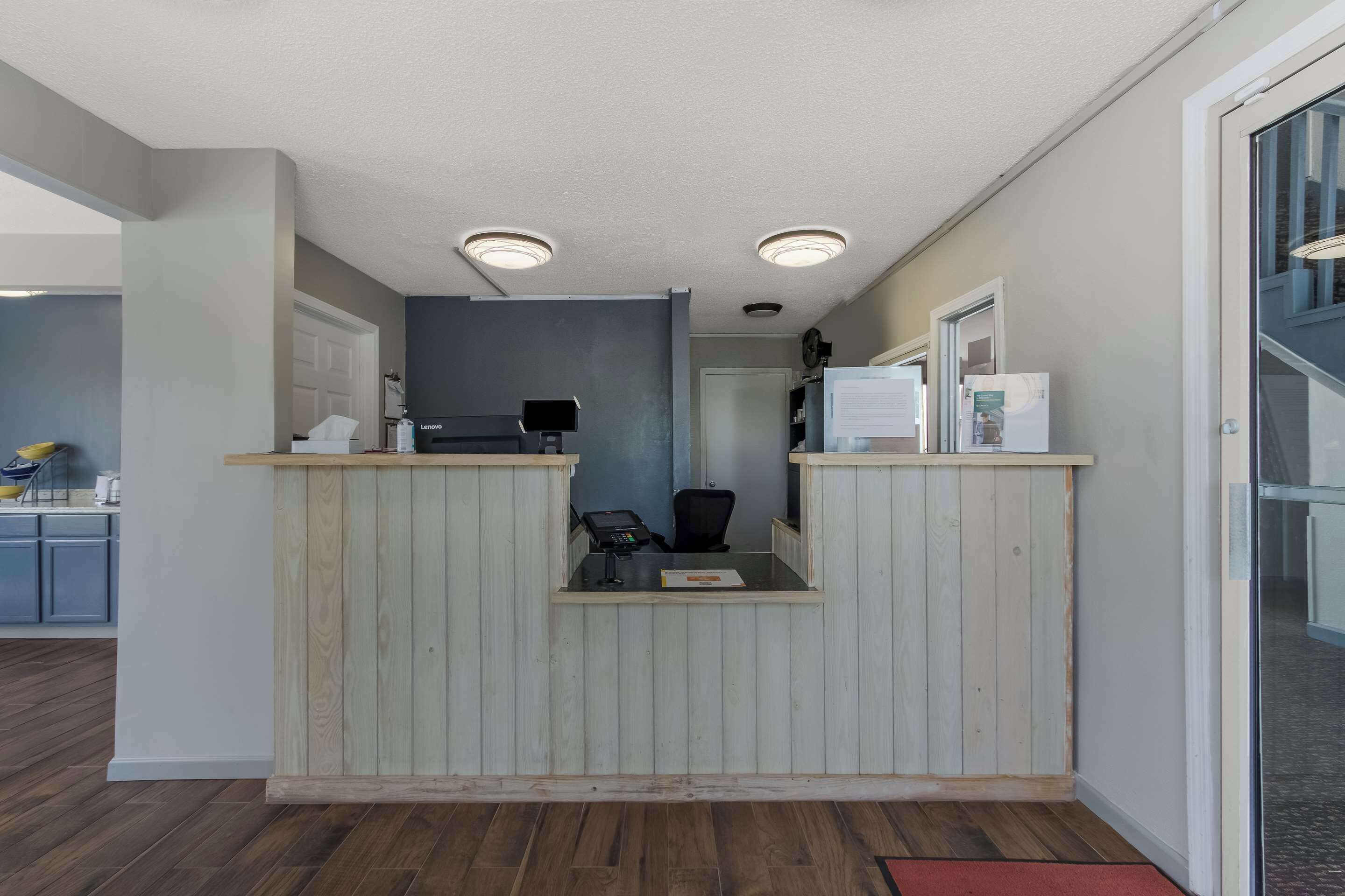 Un espace d’accueil avec un bureau en bois, un ordinateur et un téléphone.
