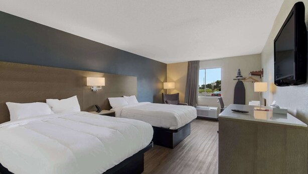 A hotel room with two beds, a desk, a TV, and a window with a view of the outside. - Econo Lodge Cherry Point (Havelock)
