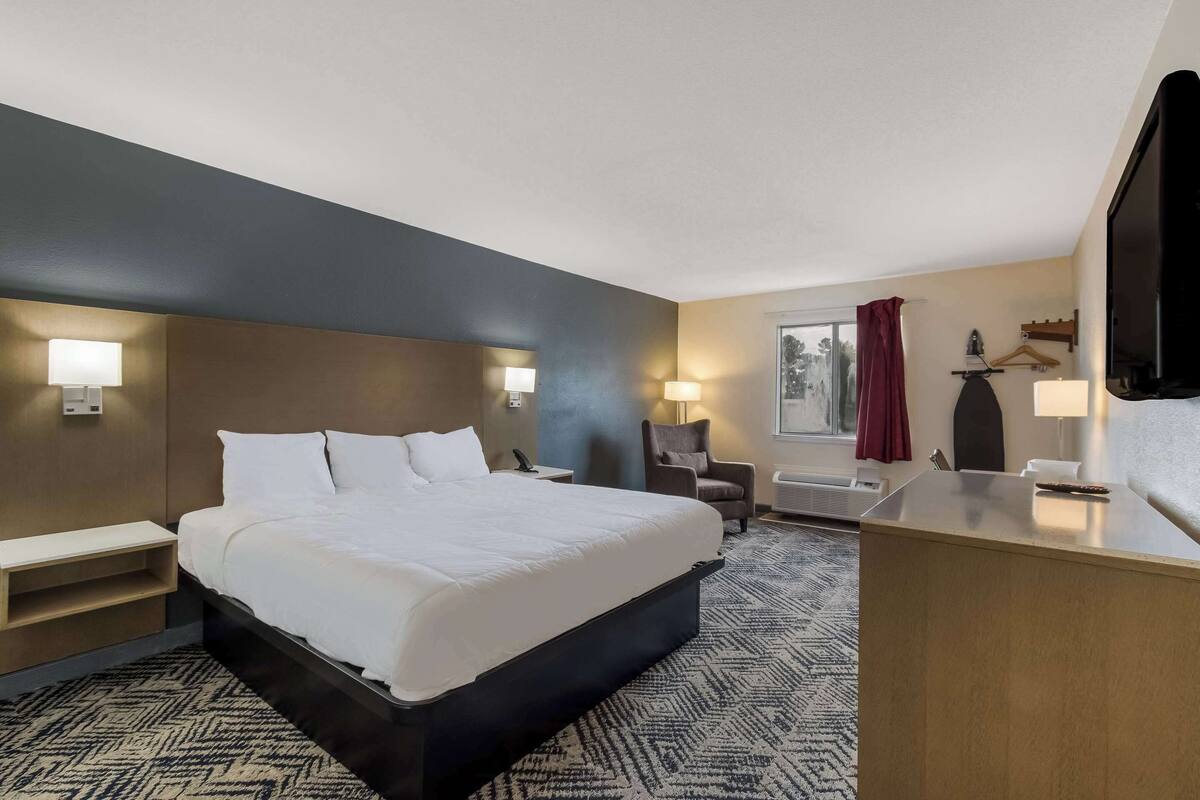 A hotel room with a large bed, bedside tables, a desk, and a TV.