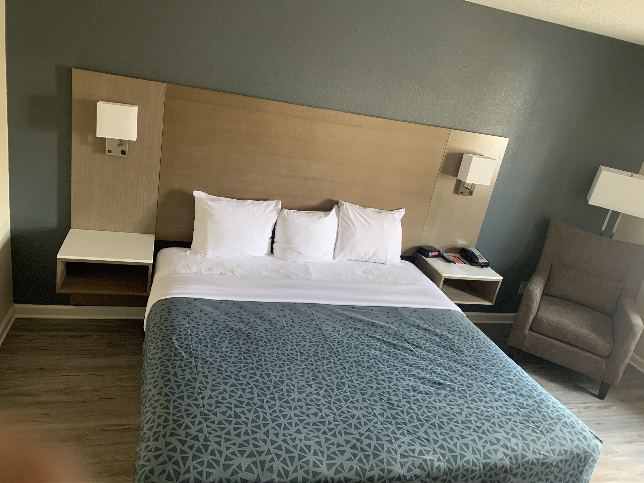 A hotel room with a bed, a chair, and two bedside tables.