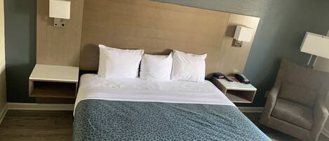 A hotel room with a bed, a chair, and two bedside tables.
