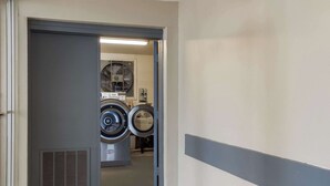 A laundry room with two stacked front-loading washing machines and a dryer. - Econo Lodge Cherry Point (Havelock)