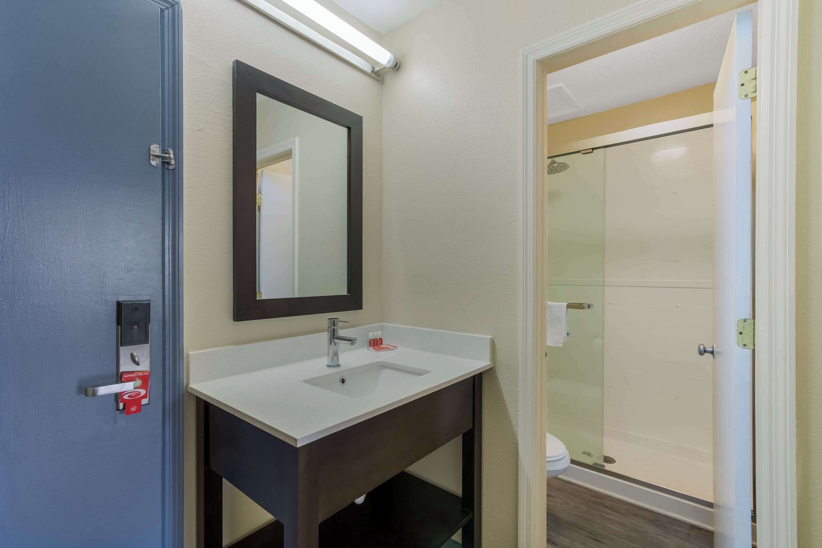 A bathroom with a white sink, dark vanity, and a glass shower enclosure.
