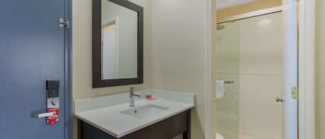 A bathroom with a white sink, dark vanity, and a glass shower enclosure.