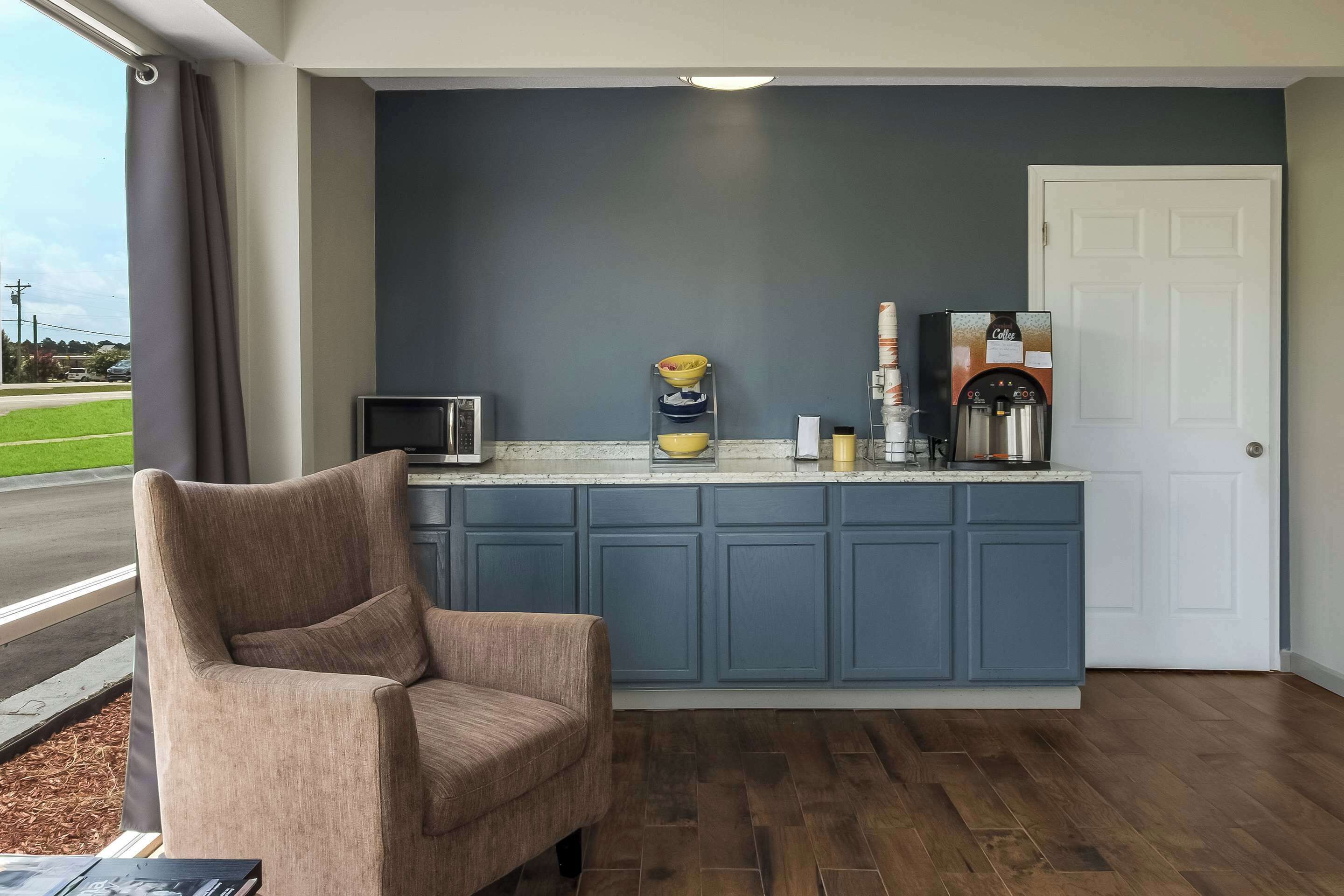 Una cocina moderna con armarios azules, una cafetera y una silla cerca de una ventana.