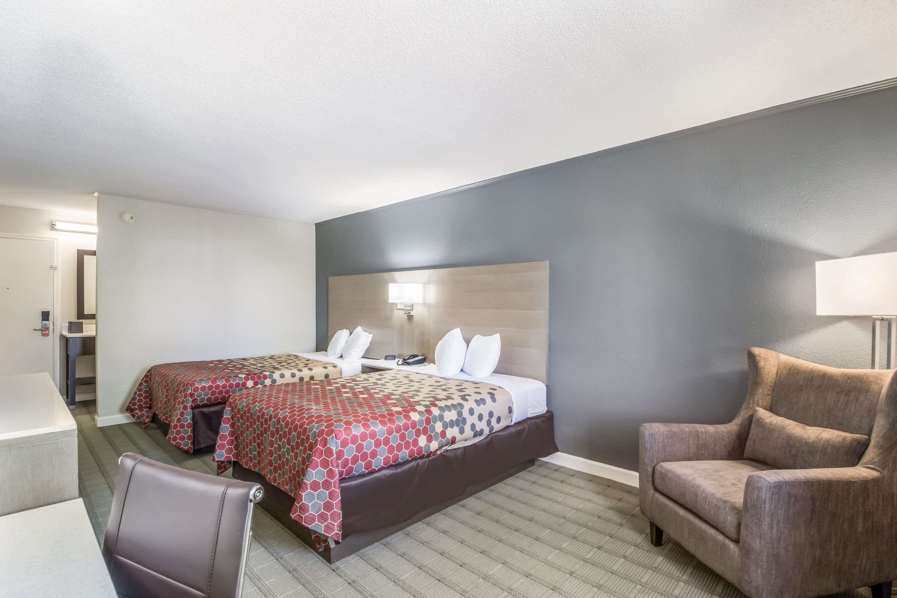 A hotel room with a bed, two bedside tables, a chair, and a lamp.