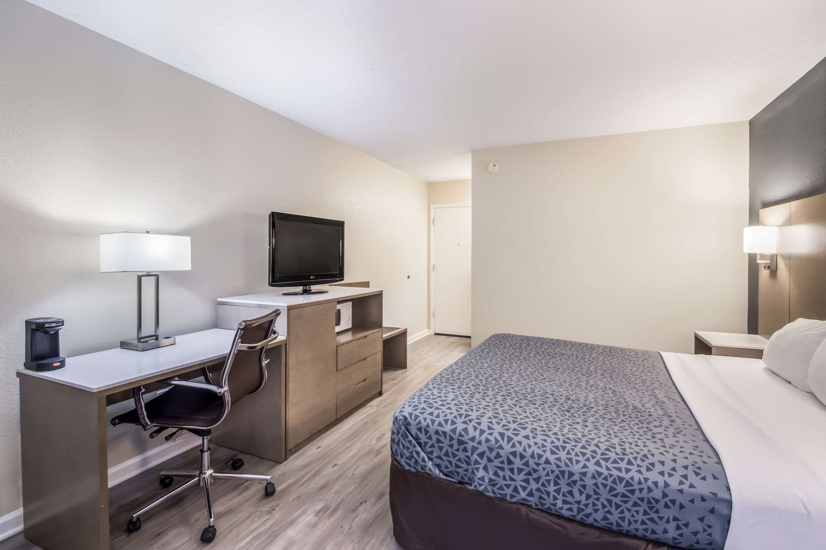Une chambre d’hôtel équipée d’un lit, d’un bureau, d’une chaise, d’une télévision et d’une lampe.