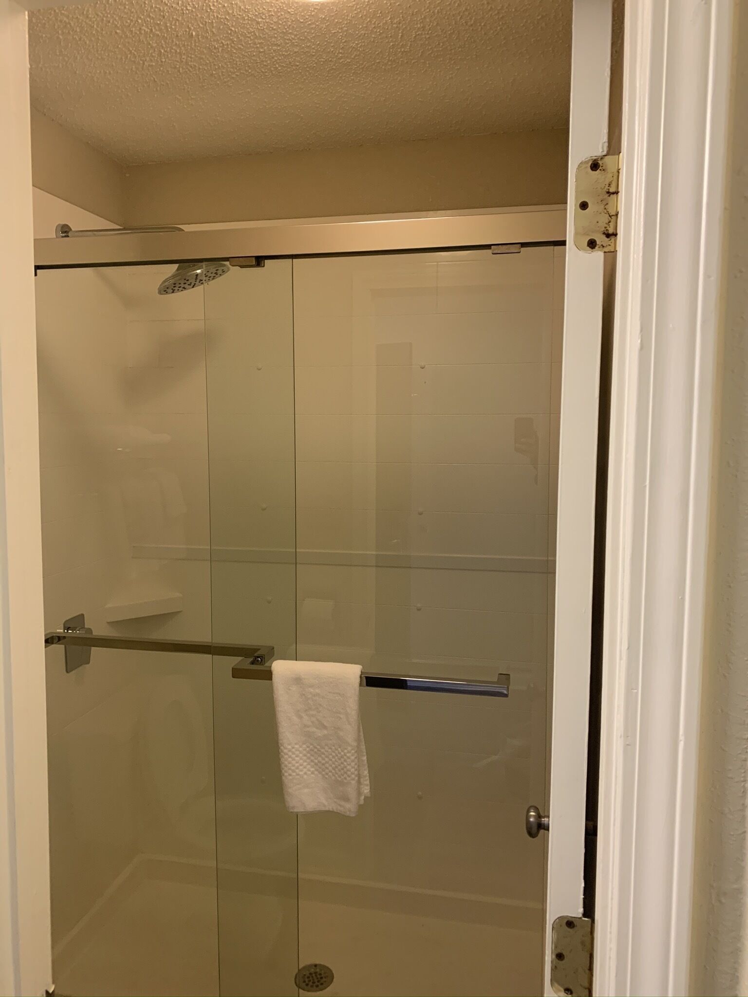 Cabina de ducha con mampara de vidrio, perchero y ducha.