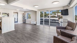 A spacious lobby with a wooden floor, a seating area with a brown sofa, and a large window offering a view of the street. - Econo Lodge Cherry Point (Havelock)