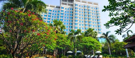 Un hotel con piscina rodeado de abundante vegetación y palmeras.