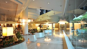 A spacious lobby with a modern design, featuring a central seating area, multiple light sources, and a glass wall providing a view of the outdoors. - Rama Gardens Hotel Bangkok (Bangkok)