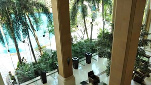 A spacious lobby with a view of a pool and palm trees, featuring a seating area with sofas and tables. - Rama Gardens Hotel Bangkok (Bangkok)