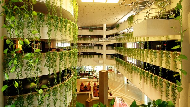 A multi-level atrium with hanging plants, a central column, and a seating area. - Rama Gardens Hotel Bangkok (Bangkok)