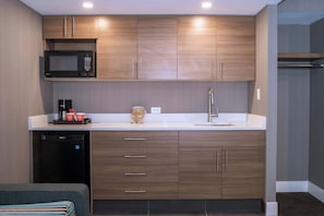 Une cuisine moderne avec des meubles en bois, un four à micro-ondes encastré, une machine à café et un évier.