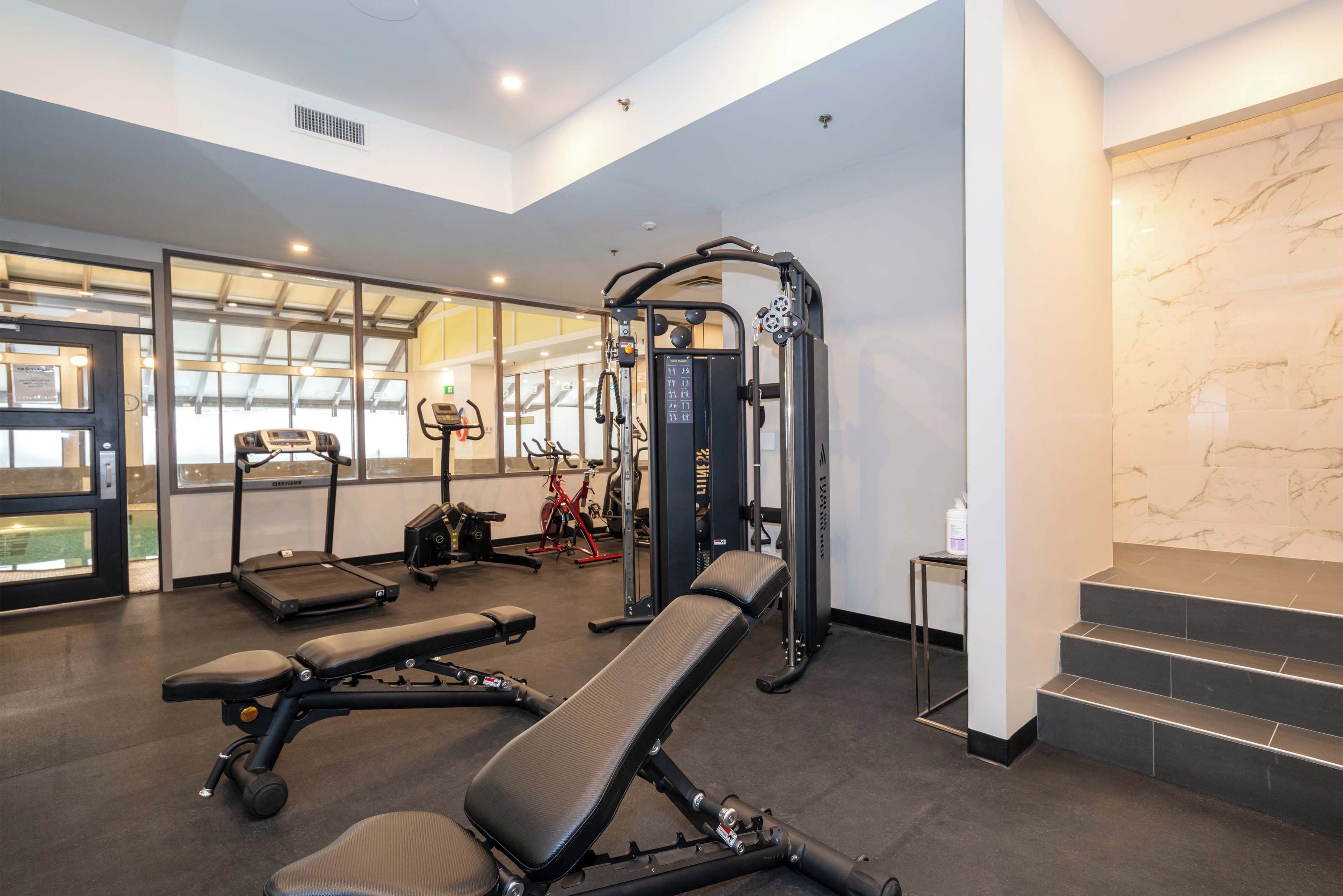 A gym with exercise equipment, benches, and a staircase.