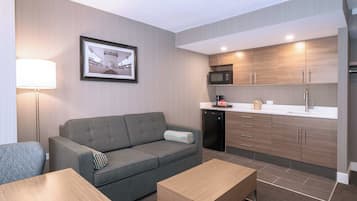 A compact living space with a sofa, a coffee table, a framed picture on the wall, a microwave, and a refrigerator.