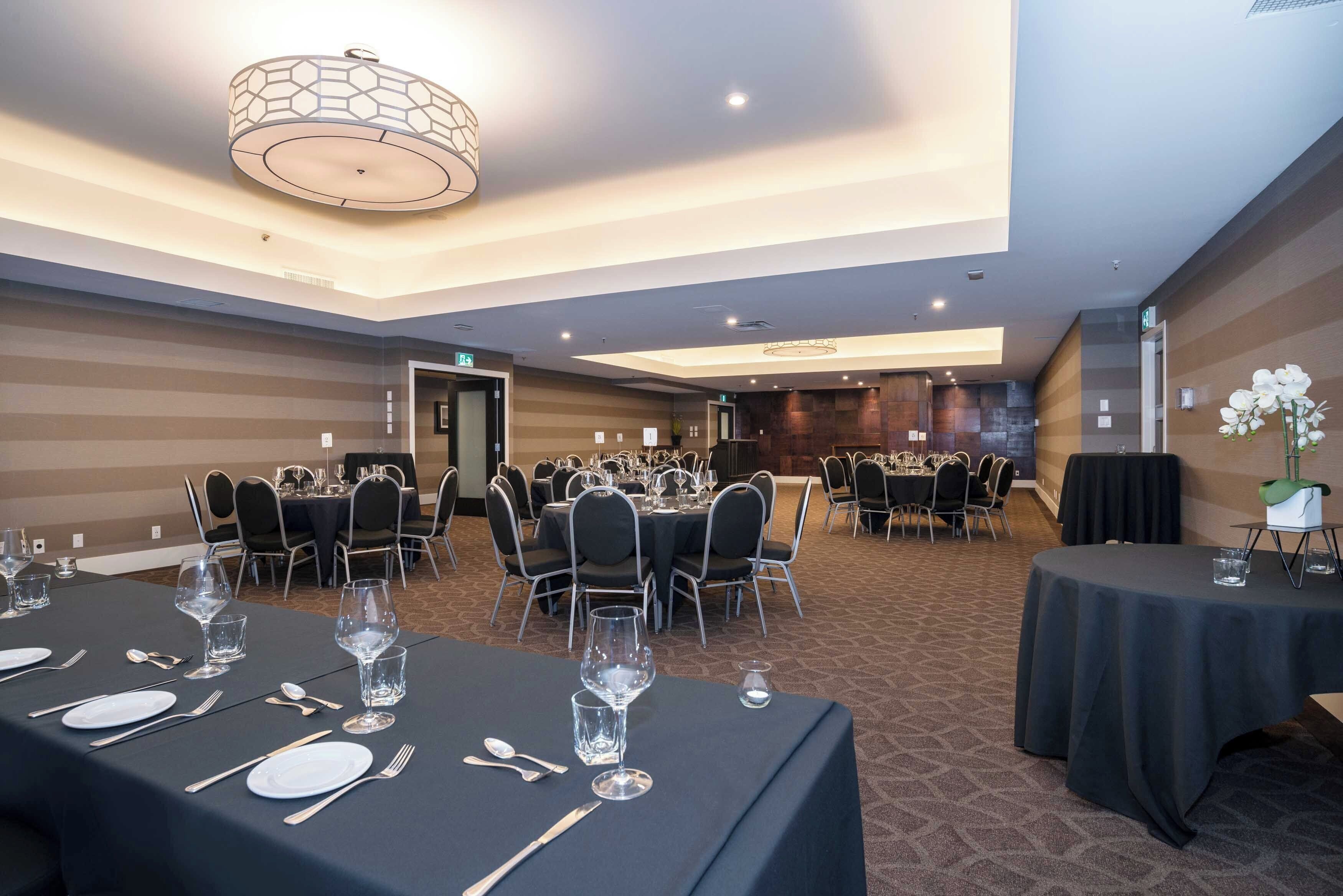 Un salón de conferencias con mesas redondas, sillas y una araña.