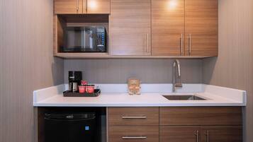 Una cocina moderna con armarios de madera, microondas integrado, cafetera y lavavajillas.