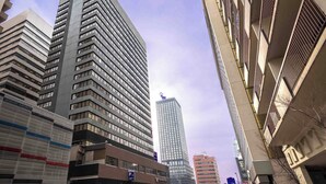 A cityscape with modern high-rise buildings, including a prominent skyscraper with a unique top design.