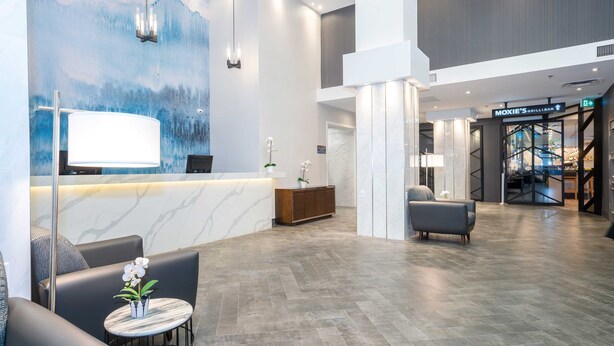 A modern reception area with a marble counter, seating, and a mural.