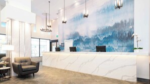 A modern reception area with a marble counter, a comfortable armchair, and a large abstract mural on the wall.