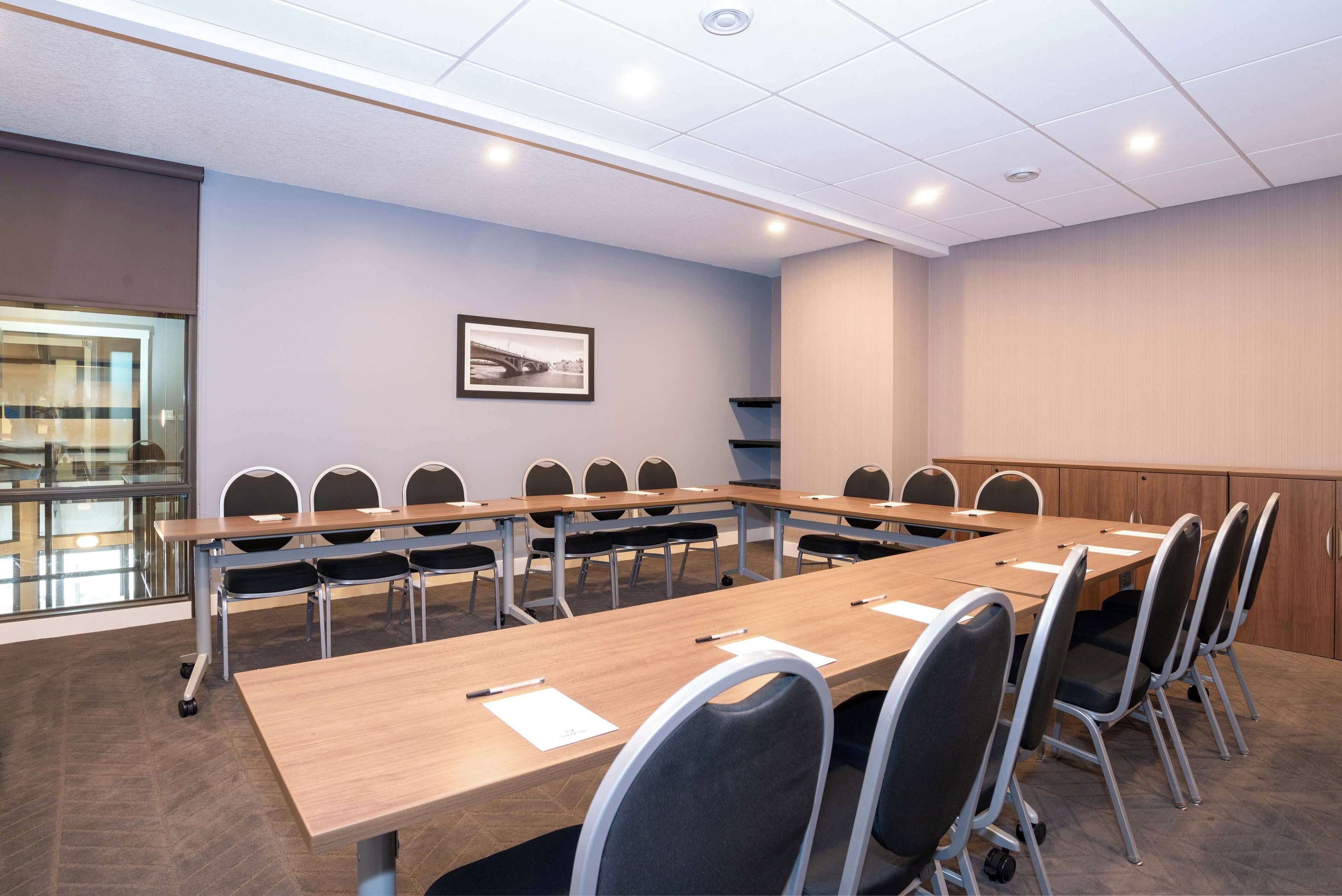 A conference room with a long table, chairs, and a framed picture on the wall.
