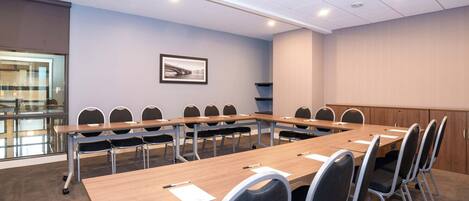 A conference room with a long table, chairs, and a framed picture on the wall.