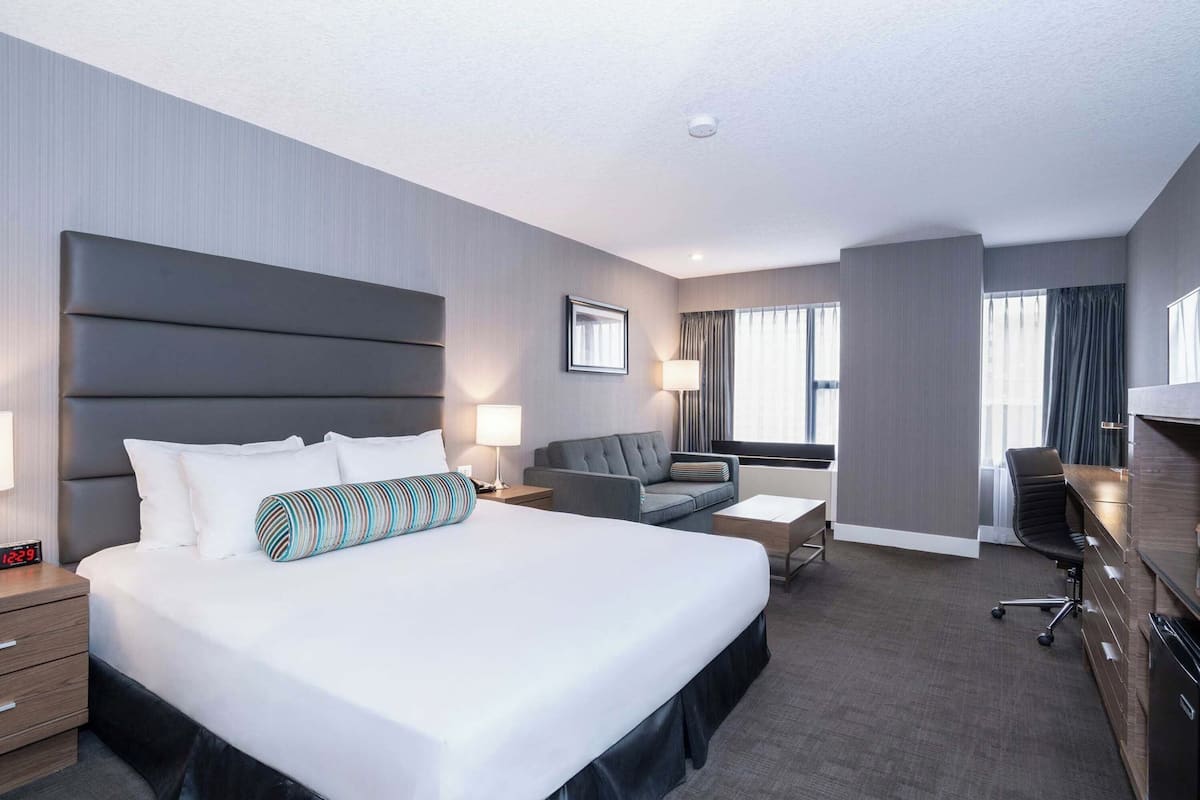 Una habitación de hotel moderna con una cama grande, un escritorio, un sofá y una silla.