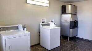A laundry room with two front-loading washers and a stainless steel refrigerator.