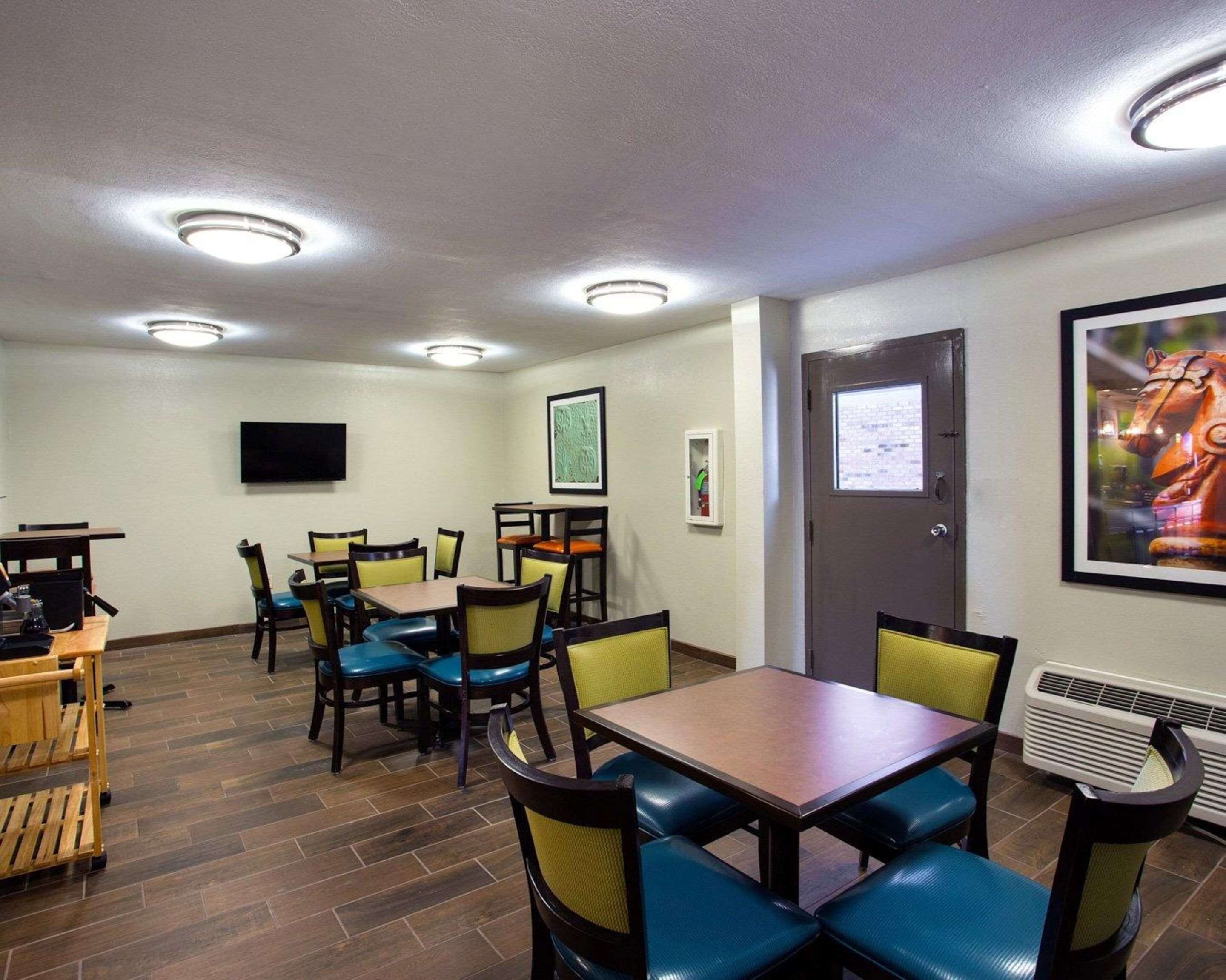A conference room with a wooden table, chairs, a flat-screen TV, and a door with a window.