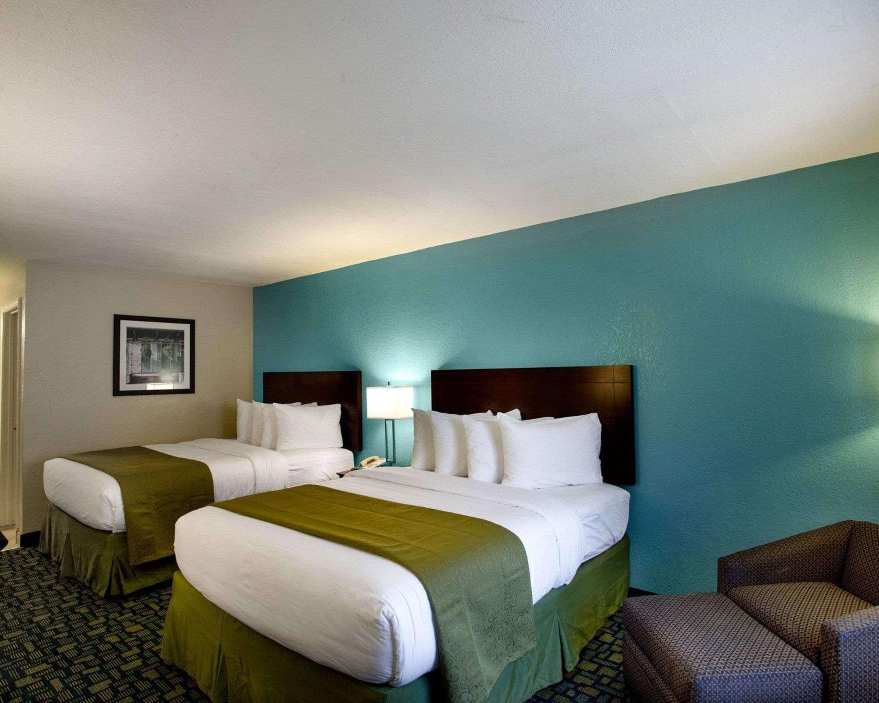 A hotel room with two beds, a desk, and a chair.