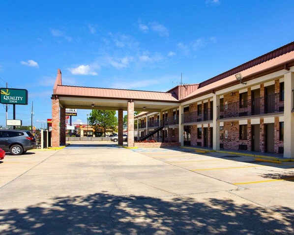 A motel with a covered parking area, multiple rooms, and a visible sign for breakfast.