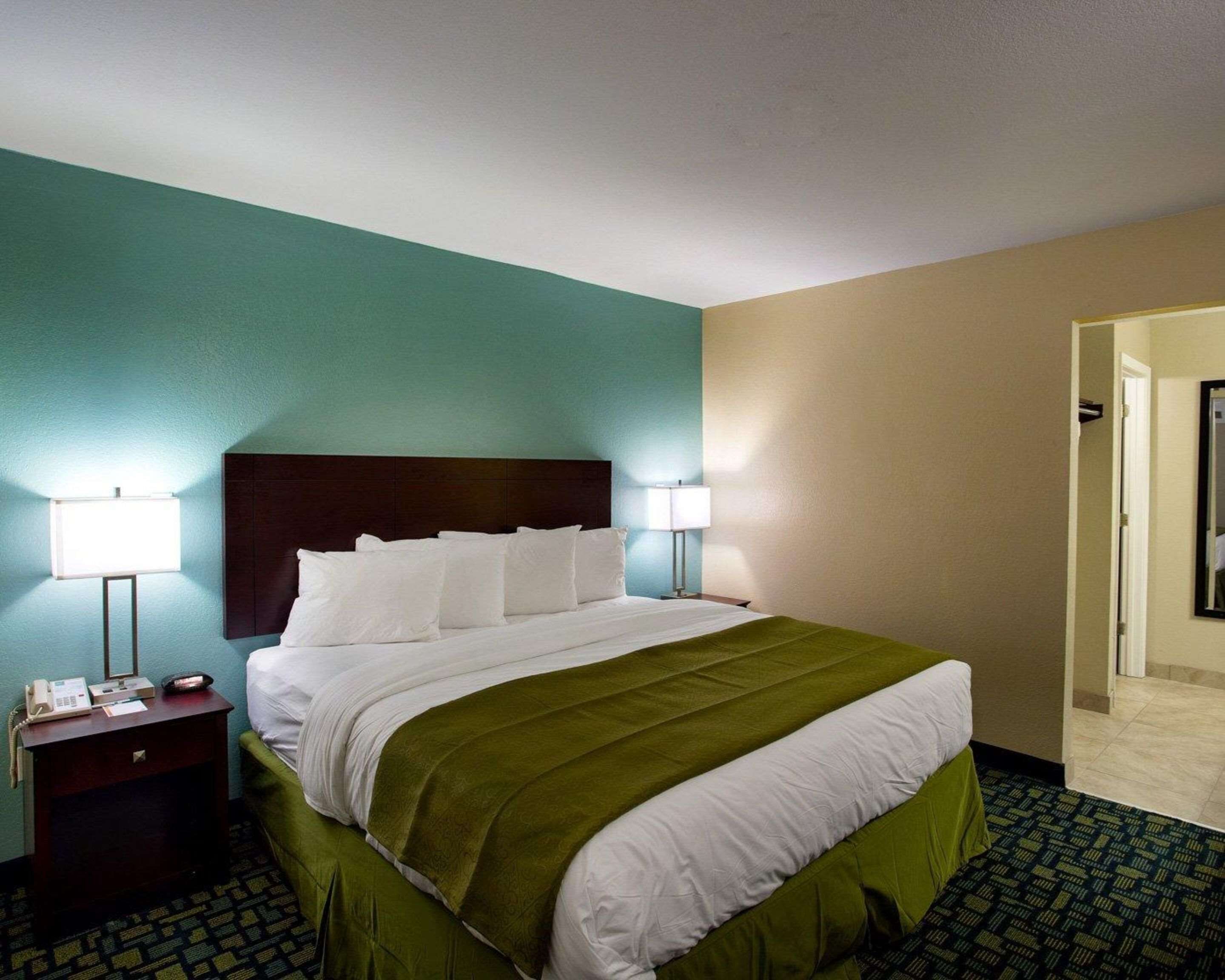 Ein Hotelzimmer mit Bett, Nachttischen und einer Tür zum Badezimmer.
