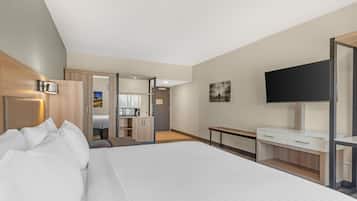A modern hotel room with a large bed, a desk, a TV, and a wardrobe.