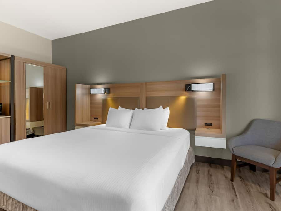 A hotel room with a large bed, a wardrobe, a desk with a computer, and a chair.