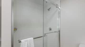 A glass-enclosed shower with a towel rack and a toilet visible.