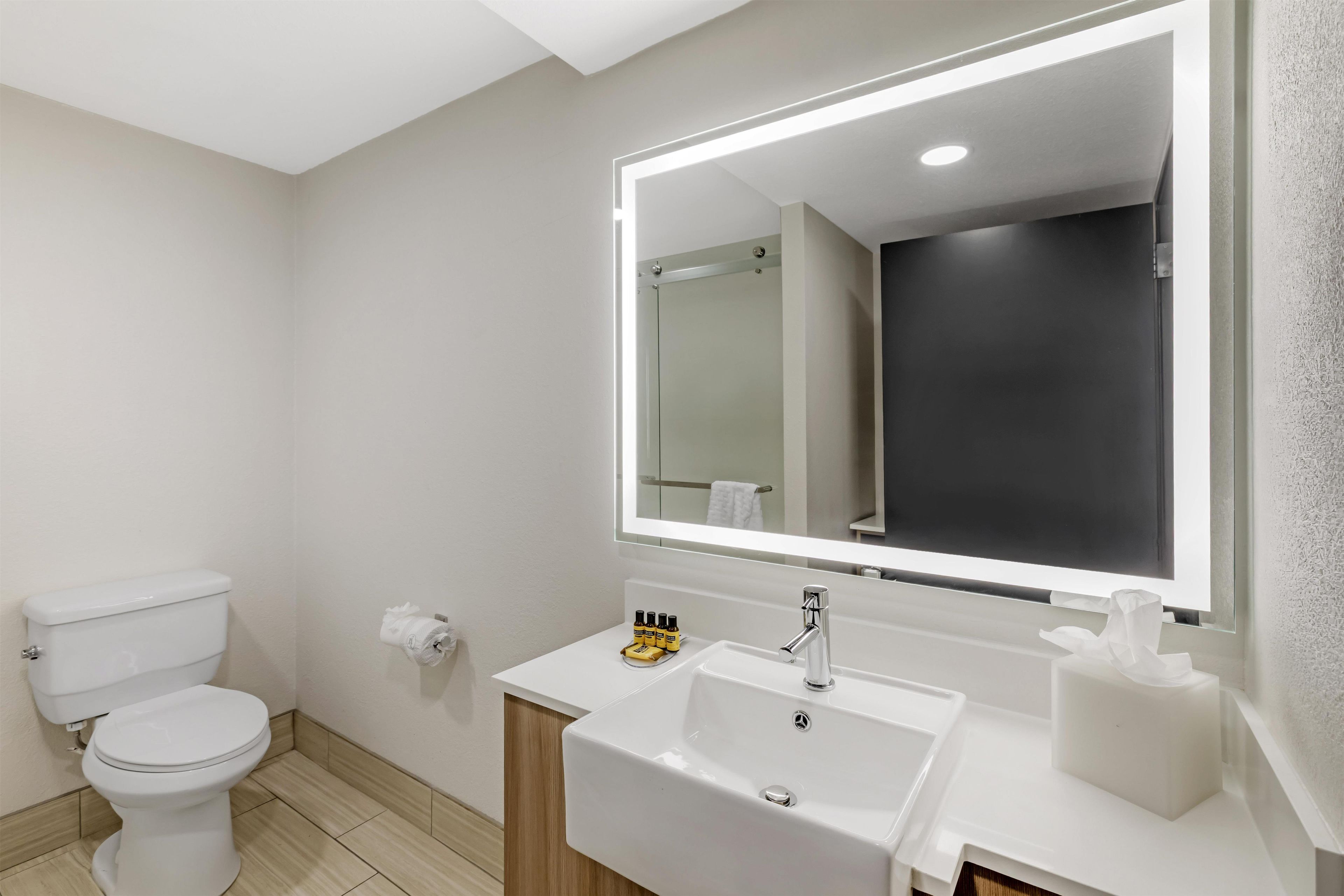 Ein modernes Badezimmer mit Toilette, Waschbecken und Spiegel.