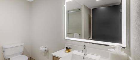 Un baño moderno con inodoro, lavamanos y espejo.