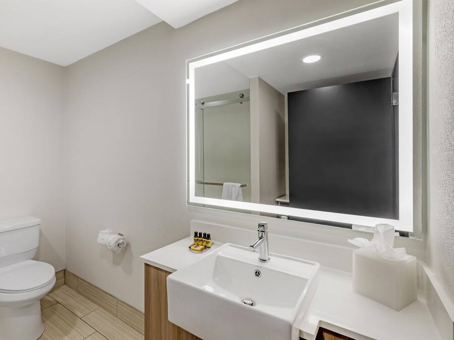 Un baño moderno con inodoro, lavamanos y espejo.