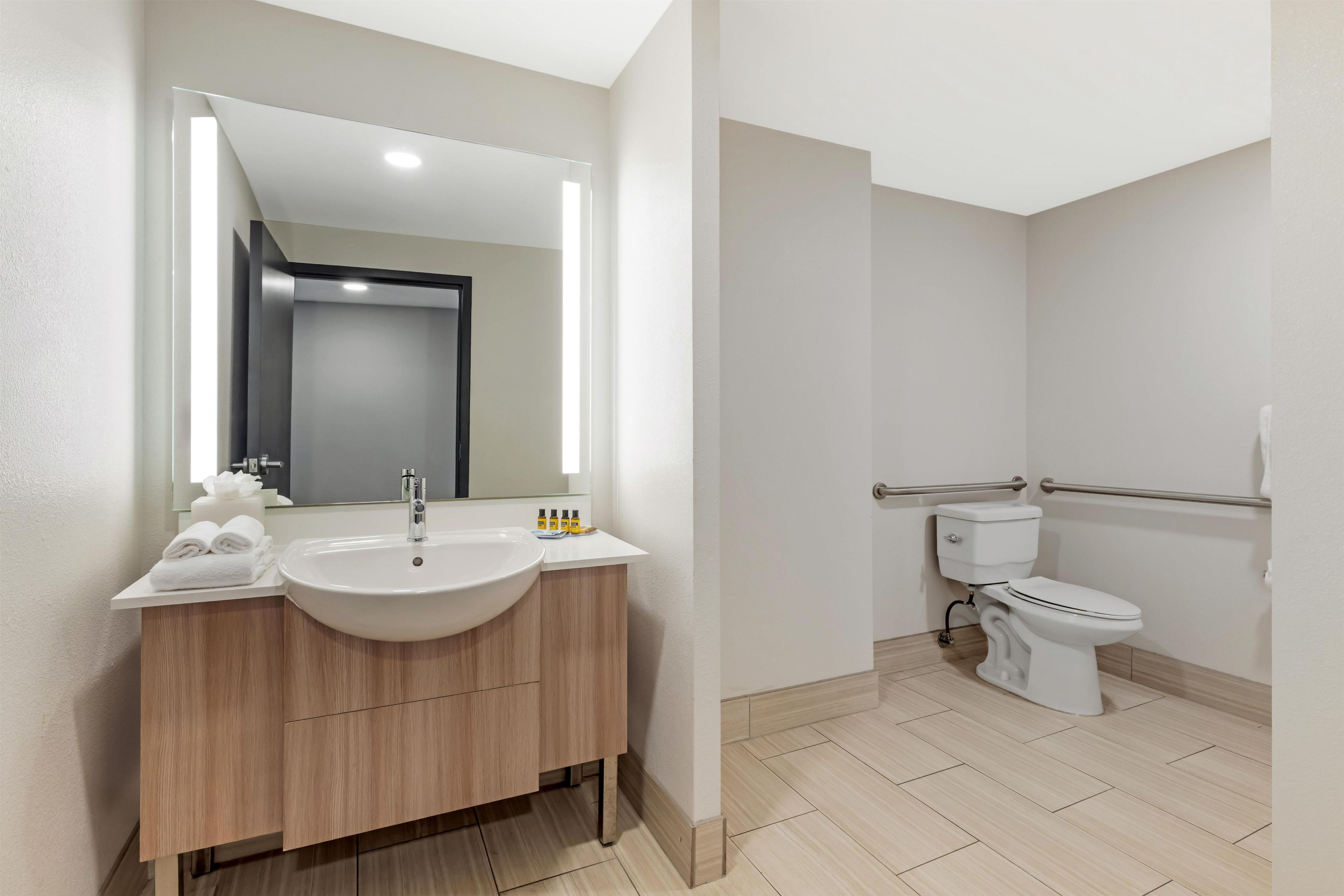 A modern bathroom with a large sink, mirror, and toilet.