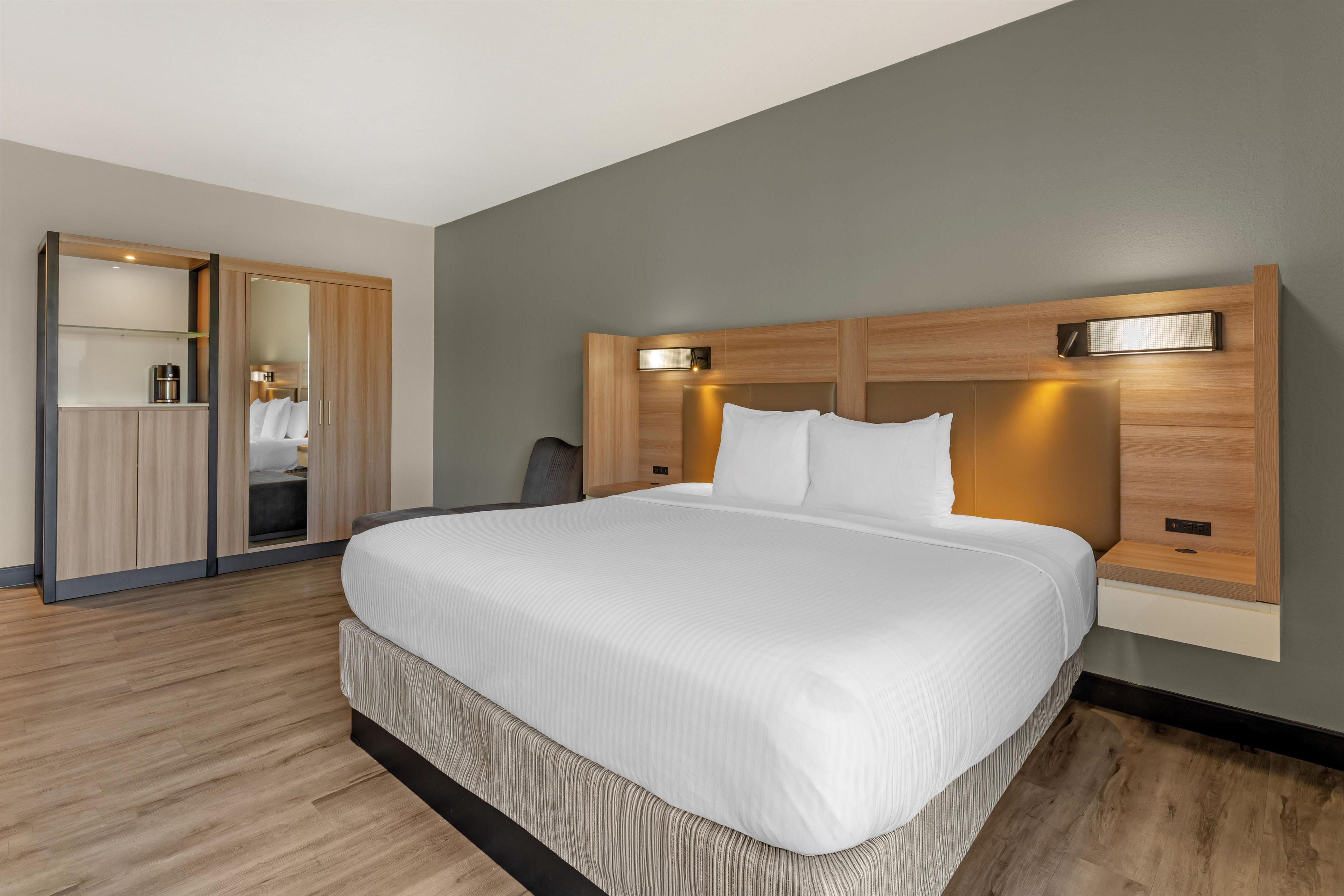 Une chambre d’hôtel moderne avec un grand lit, une armoire en bois et un espace bureau.