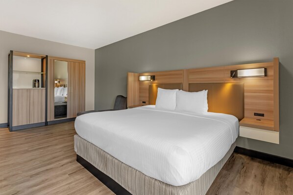 Une chambre d’hôtel moderne avec un grand lit, une armoire en bois et un espace bureau.