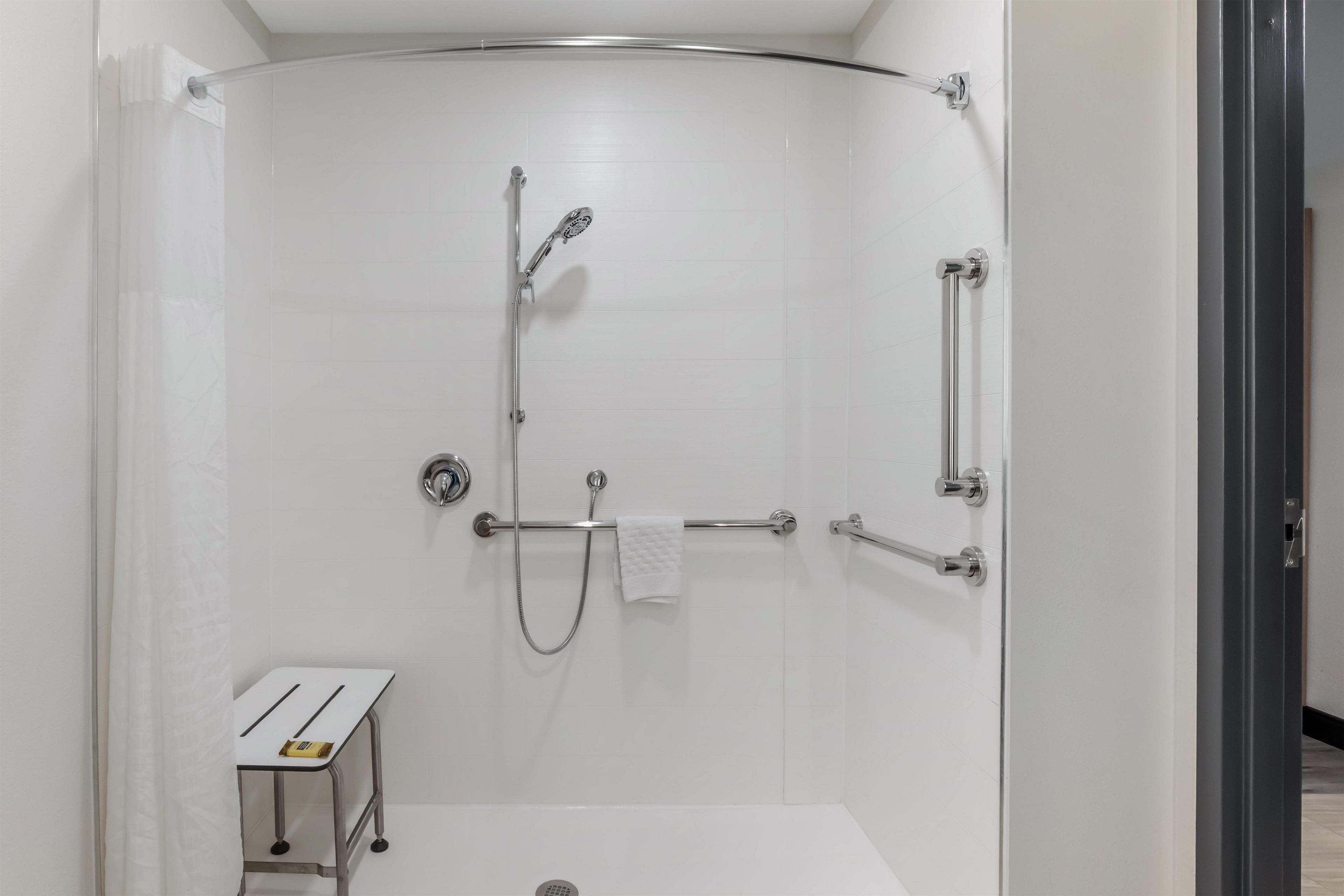A modern shower enclosure with a handheld showerhead, a handheld showerhead, and a towel bar.