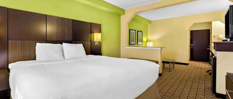 A hotel room with a large bed, a desk, and a television.