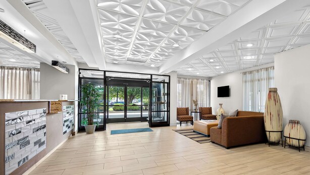 A modern hotel lobby with a wooden floor, a reception desk, a sofa, and a surfboard display. - Best Western Knoxville Suites - Downtown (Knoxville)