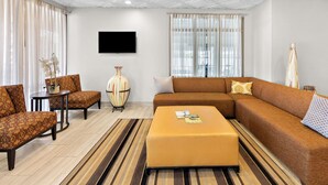 A modern living room with a sectional sofa, a small round table, and a large vase. - Best Western Knoxville Suites - Downtown (Knoxville)