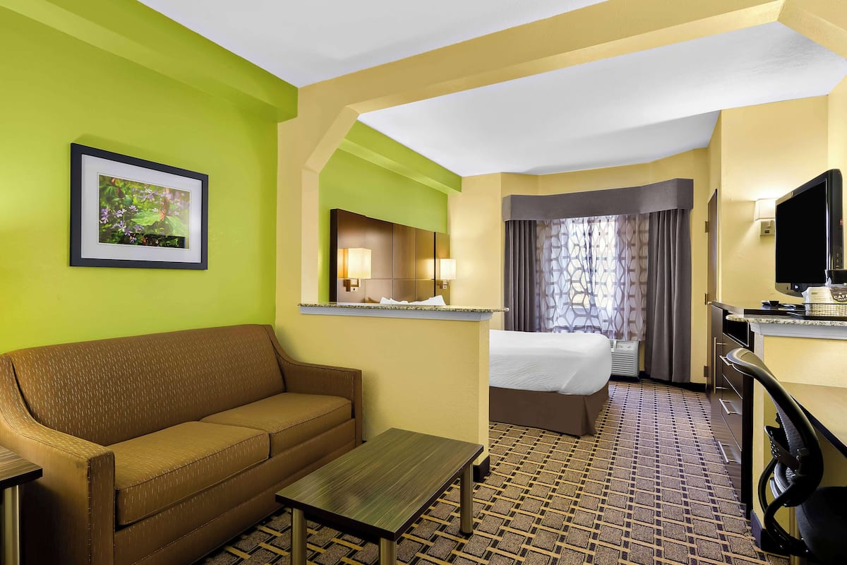 A hotel room with a sofa, a bed, a desk, and a television.
